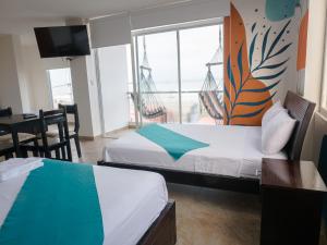 a room with two beds and a table and a window at Margaritas Palace Hotel in Canoa