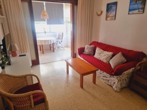 a living room with a red couch and a table at Apartamento en Playa del Inglés Los Mangos in Playa del Ingles