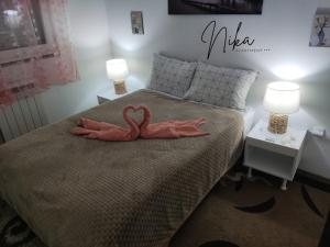 two pink flamingos sitting on a bed with two lamps at Apartman Nika in Kragujevac