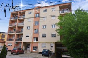 a building with cars parked in front of it at Apartman Nika in Kragujevac