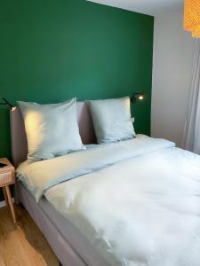 1 cama con almohadas blancas y pared verde en Kleines Glück zentral mit Balkon und Parkplatz, en Gössweinstein
