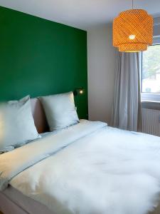 1 dormitorio con 1 cama blanca grande y pared verde en Kleines Glück zentral mit Balkon und Parkplatz, en Gössweinstein