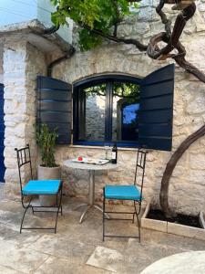 a table and chairs in front of a stone wall at VILLA MOST Tisno in Tisno