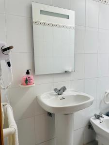 Baño blanco con lavabo y espejo en Apartamentos azayara en Frontera
