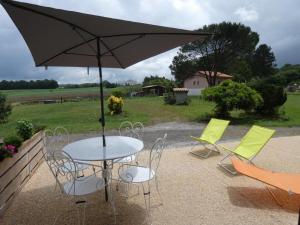 - une table et des chaises avec un parasol sur la terrasse dans l'établissement Le petit saou du becq, à Saint-Lon-les-Mines
