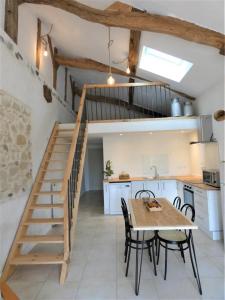uma cozinha e sala de jantar com uma mesa e uma escada em Le petit saou du becq em Saint-Lon-les-Mines