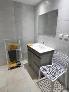 ein Badezimmer mit einem Waschbecken, einem Stuhl und einem Spiegel in der Unterkunft Le petit saou du becq in Saint-Lon-les-Mines