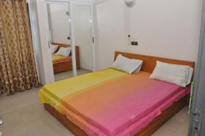 a bedroom with a large bed with colorful sheets at Maison Houdji, près de la lagune in Cotonou