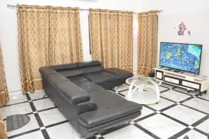a living room with a black leather couch and a tv at Maison Houdji, près de la lagune in Cotonou