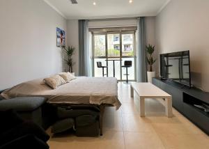 Schlafzimmer mit einem Bett, einem TV und einem Tisch in der Unterkunft Reinapart Patacona Beach 36 in Valencia