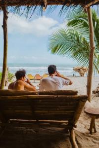 dwóch mężczyzn siedzących na ławce na plaży w obiekcie Lote 10 Glamping w mieście Guachaca