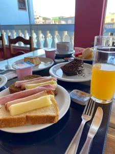 una mesa con platos de comida y un vaso de zumo de naranja en Pousada Paraíso dos Corais, en Arraial do Cabo