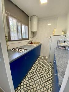 a kitchen with blue cabinets and a white refrigerator at La calma de Tossa in Girona