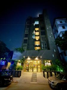 a tall building at night with a car parked in front at The Elite Residence Dhaka in Dhaka