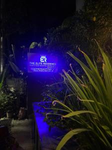a purple lighted sign in a garden at night at The Elite Residence Dhaka in Dhaka
