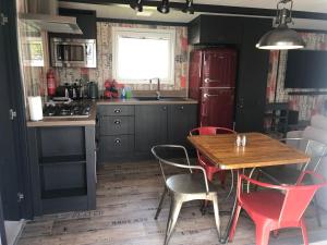 a kitchen with a wooden table and red chairs at Unique 4/6 berth 2 bed tribeca with great views in Bembridge