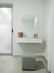 un bagno bianco con specchio rotondo e ottomana di Dionis House a Shkodër