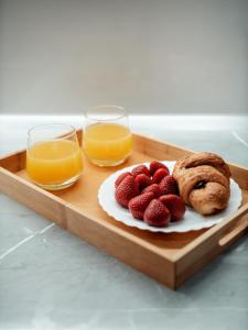 a tray with two glasses of orange juice and strawberries at Dionis House in Shkodër