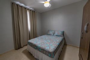 a small bedroom with a bed and a window at Lindo apartamento 2 quartos com wifi in Rio das Ostras