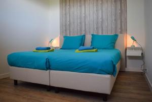 een slaapkamer met een bed met blauwe lakens en blauwe kussens bij Roggebroek 29 in Stavoren