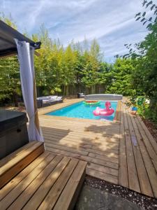 a backyard pool with a wooden deck and a pool float at Villa Moya, dependance privée Piscine & Spa in Châteauneuf-sur-Loire