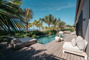 un patio con piscina, sillas y palmeras en Kontiki Beach Resort, en Willemstad