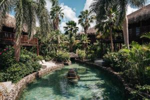 a pool in the middle of a resort with palm trees at Kontiki Beach Resort in Willemstad