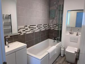a bathroom with a tub and a sink and a toilet at Studland View Cottage in Studland