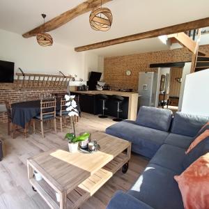 uma sala de estar com um sofá azul e uma mesa em L'écurie d'antan em Hautot-Saint-Sulpice