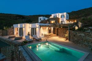 a villa with a swimming pool in front of a house at KaYa Tinos Luxury Villa - Aeolus in Agios Romanos