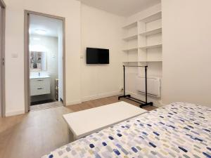 - une chambre avec un lit et une télévision à écran plat dans l'établissement Appartement 1 Chambre, cuisine, coin salon, salle de bain, à Saint-Claude