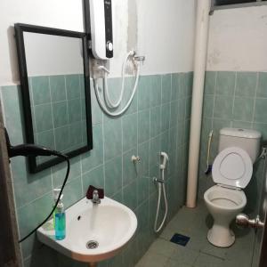 uma casa de banho com um lavatório, um WC e um espelho. em Myera Hotel em Banting