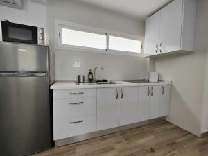 een keuken met witte kasten en een roestvrijstalen koelkast bij The Sound Of Ocean Waves in San Agustin