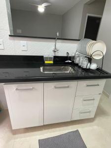 a kitchen with a sink and a black counter top at Lindo apartamento 2 quartos com wifi in Rio das Ostras