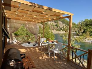 une terrasse en bois avec une table, des chaises et une rivière dans l'établissement Canyon Tiny House, à Manavgat