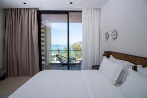 a bedroom with a large white bed and a balcony at Hotel Olympia Touristic Village in Vlorë