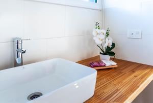 baño con lavabo blanco y jarrón de flores en Happy Host - Casas Calafate VLA en Villa La Angostura