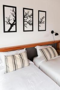 2 camas en una habitación con cuadros enmarcados en la pared en Happy Host - Casas Calafate VLA en Villa La Angostura