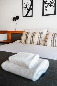 un par de toallas blancas sentadas en una cama en Happy Host - Casas Calafate VLA en Villa La Angostura