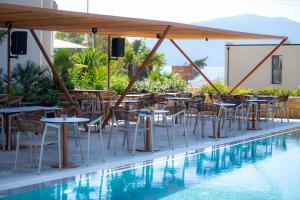 a restaurant with tables and chairs next to a swimming pool at Hotel Olympia Touristic Village in Vlorë