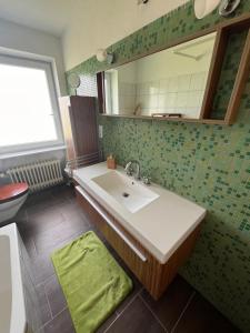 ein Bad mit einem Waschbecken und einem Spiegel in der Unterkunft Ruhige Ferienwohnung im Saarland in Schiffweiler
