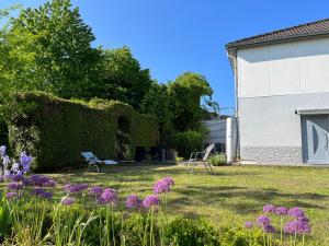 einen Garten mit zwei Stühlen und lila Blumen in der Unterkunft Ruhige Ferienwohnung im Saarland in Schiffweiler