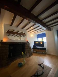 a living room with a table and a fireplace at 1750's cottage with open fire and beams in Upholland