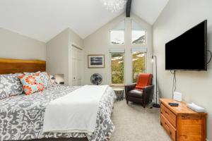 een slaapkamer met een bed, een tv en een stoel bij Alyeska Slopeside in Girdwood