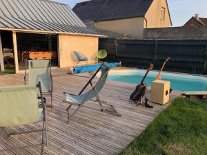 um deque de madeira com cadeiras e uma piscina em Maison de ville atypique em Le Molay-Littry