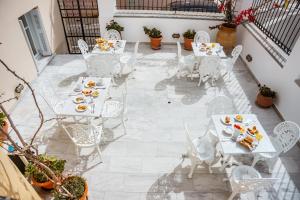 une terrasse avec des tables et des chaises blanches et de la nourriture. dans l'établissement Archontiko Eleni Hotel, à Andros