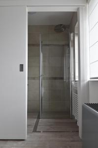 La salle de bains est pourvue d'une douche avec une porte en verre. dans l'établissement de minnetuin, à Wachtebeke