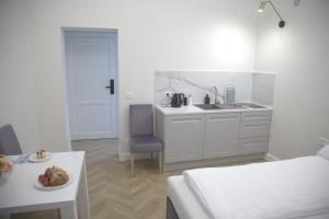 a white kitchen with a sink and a table at Apartamenty al Mare Sopot in Sopot