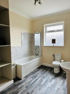 a bathroom with a tub and a toilet and a sink at Cosy house in Wombwell in Barnsley