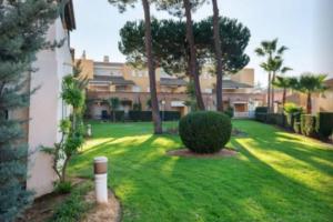 ein Hof mit einem grünen Rasen mit Bäumen und einem Gebäude in der Unterkunft Palo verde-Golf-Playa-Islantilla in Islantilla
